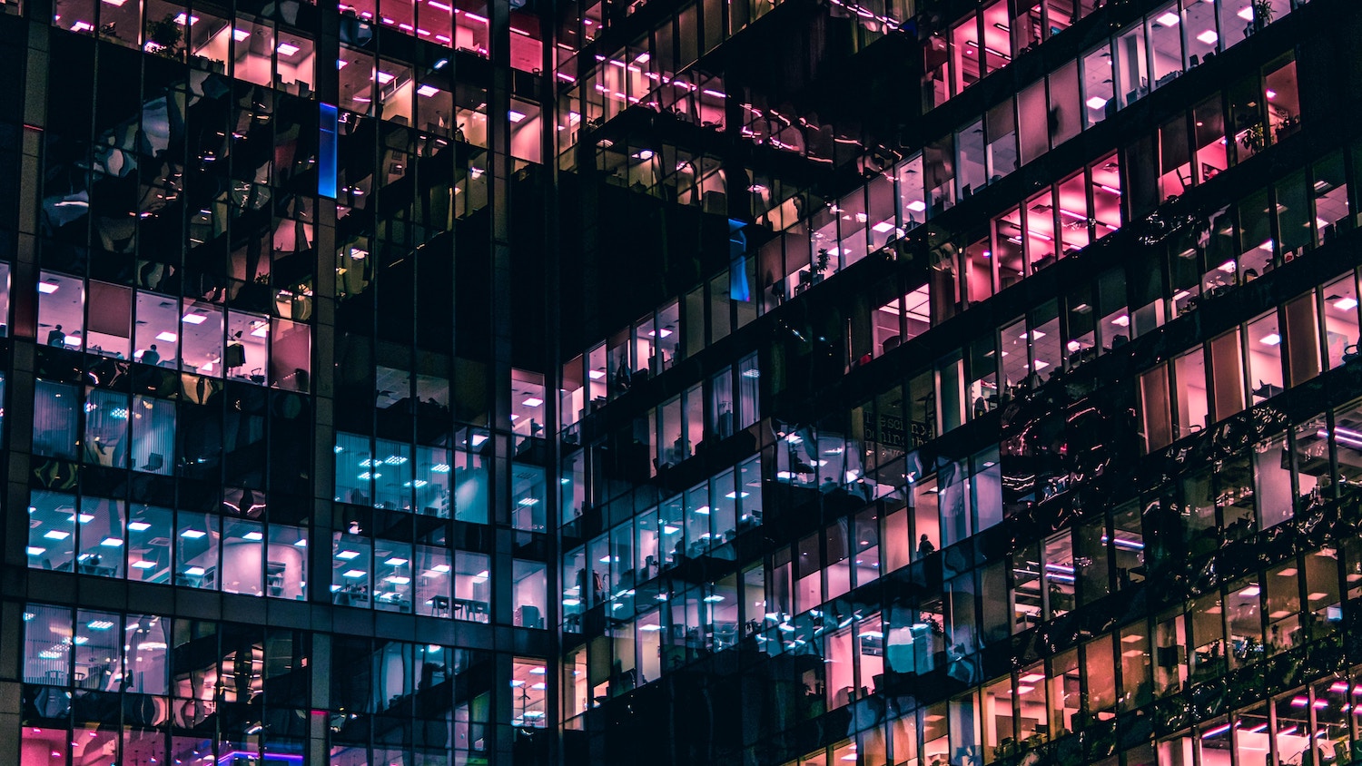 Office building at night with lights on and cybersecurity professionals working