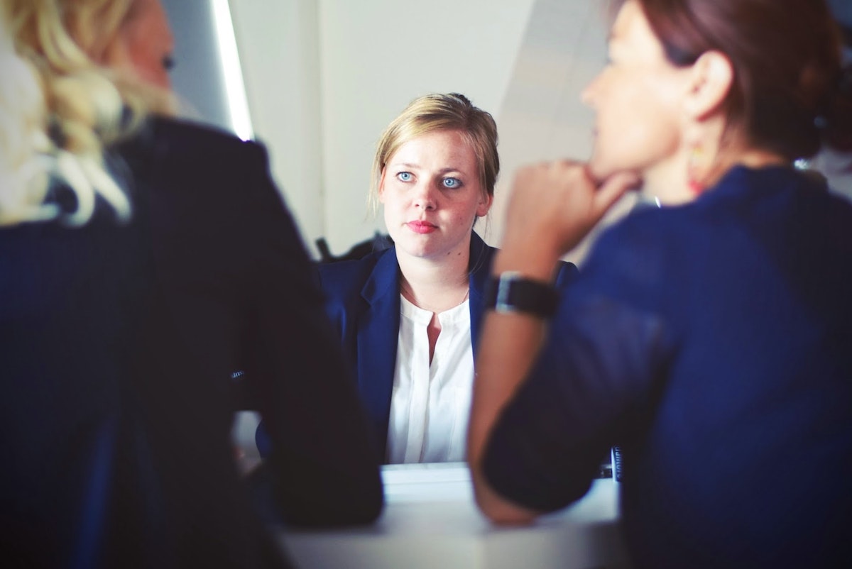 Two female in business attire interviewing a third female job candidate for a project management consultant position